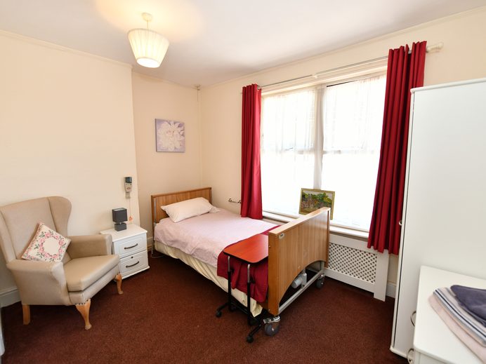 Resident's bedroom with profiling bed and armchair